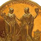 Médaille dorée, sur laquelle sont représentées deux figures féminines et surmontéer de l'inscription "Encouragements et récompenses à l'industrie