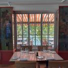 intérieur de restaurant, table dressée au premier plan, chaises et table sur une terrasse en arrière plan