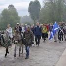 groupe de personnes marchant sur un pont de pierres, des enfants sont à dos d'ânes
