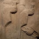 Sculture en relief de deux personnages en vêtements hamples, tenant une pince et un coin 