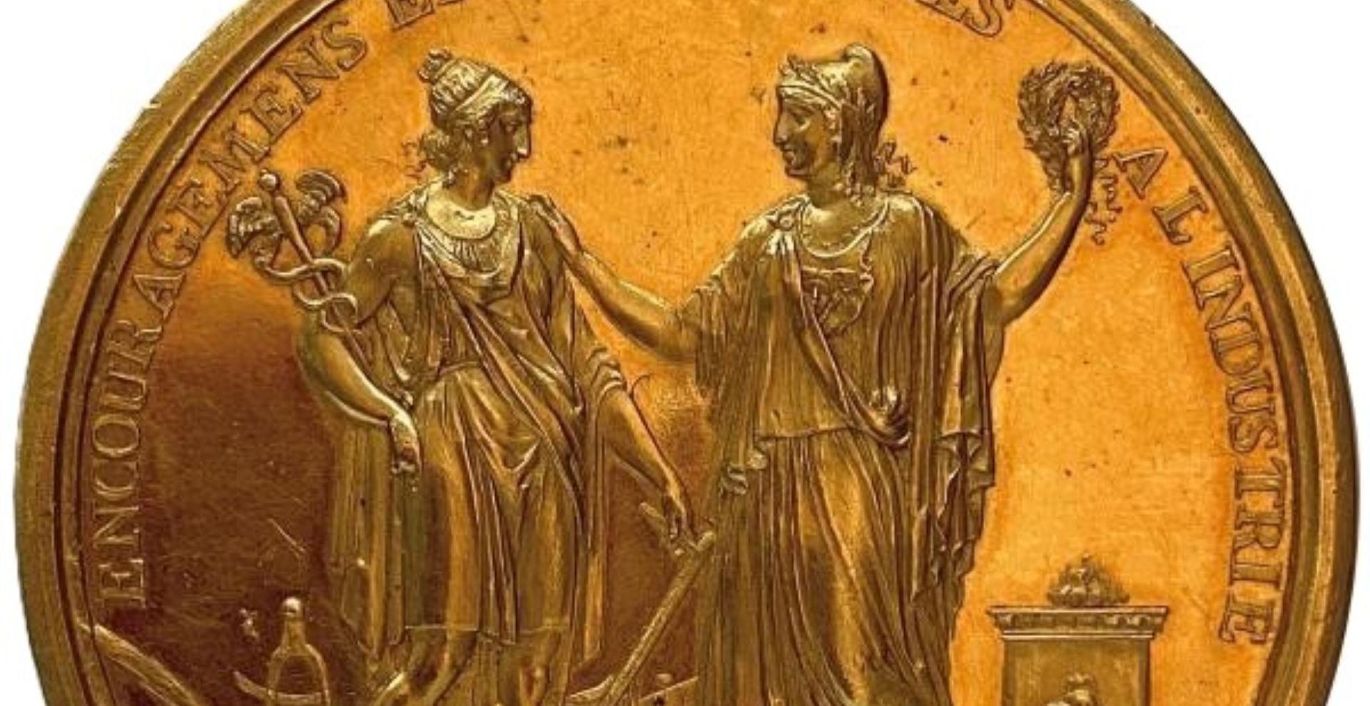Médaille dorée, sur laquelle sont représentées deux figures féminines et surmontéer de l'inscription "Encouragements et récompenses à l'industrie