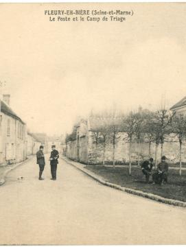 Carte postale, vue d'une rue de Fleury-en-Brie, des hommes en uniformes et armés sont postés dans la rue.