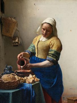 Femme vêtue portant un bonnet blanc et versant du lait dans un récipient.