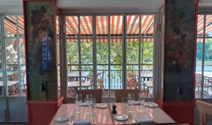intérieur de restaurant, table dressée au premier plan, chaises et table sur une terrasse en arrière plan