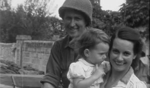 Photographie d'un soldat et devant lui une femme portant un enfant