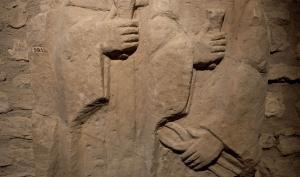 Sculture en relief de deux personnages en vêtements hamples, tenant une pince et un coin 