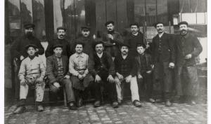 groupe d'hommes, six sont assis au premier rang et sept se tiennent debout derrière, certains portent des casquettes