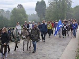 groupe de personnes marchant sur un pont de pierres, des enfants sont à dos d'ânes