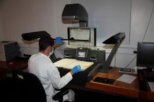 Vue du photographe manipulant un registre dans un scanner adapté aux registres