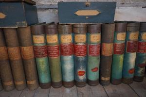 photographies de plusieurs registres comptables aux reliures colorés et étiquettes rouges