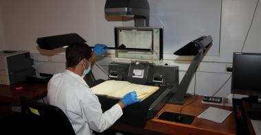 Vue du photographe manipulant un registre dans un scanner adapté aux registres