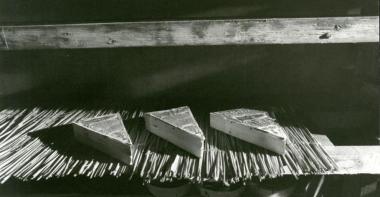 trois blocs de fromages disposés sur des clayons de paille