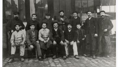groupe d'hommes, six sont assis au premier rang et sept se tiennent debout derrière, certains portent des casquettes
