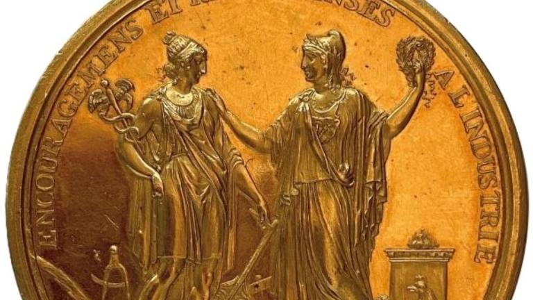 Médaille dorée, sur laquelle sont représentées deux figures féminines et surmontéer de l'inscription "Encouragements et récompenses à l'industrie