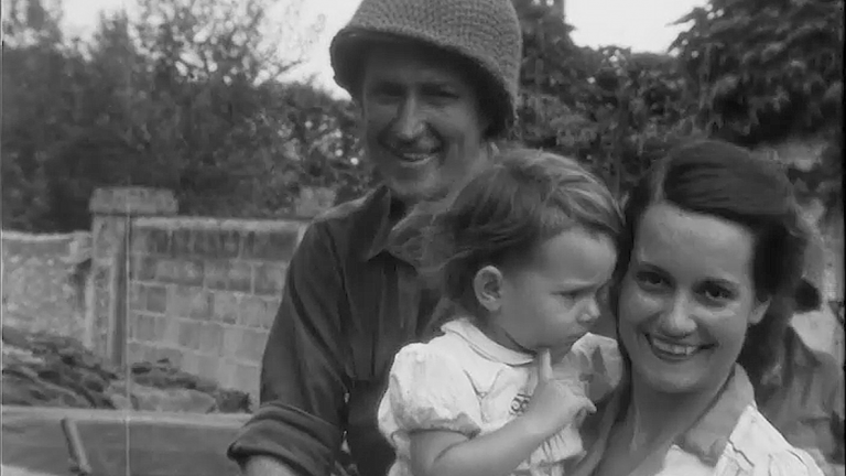 Photographie d'un soldat et devant lui une femme portant un enfant