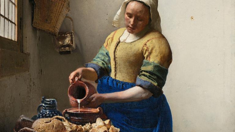 Femme vêtue portant un bonnet blanc et versant du lait dans un récipient.
