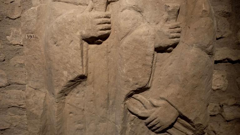 Sculture en relief de deux personnages en vêtements hamples, tenant une pince et un coin 