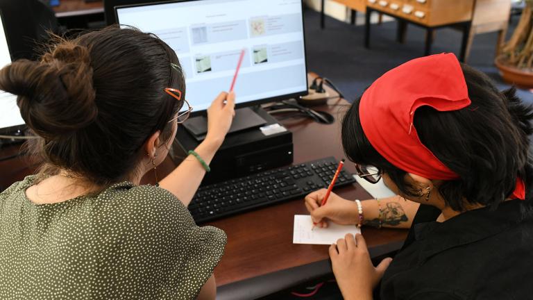 Lectrices faisant une recherche sur ordinateur en salle de lecture.
