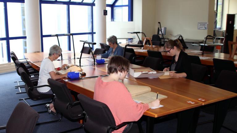 Lecteurs consultant des documents en salle de lecture des Archives